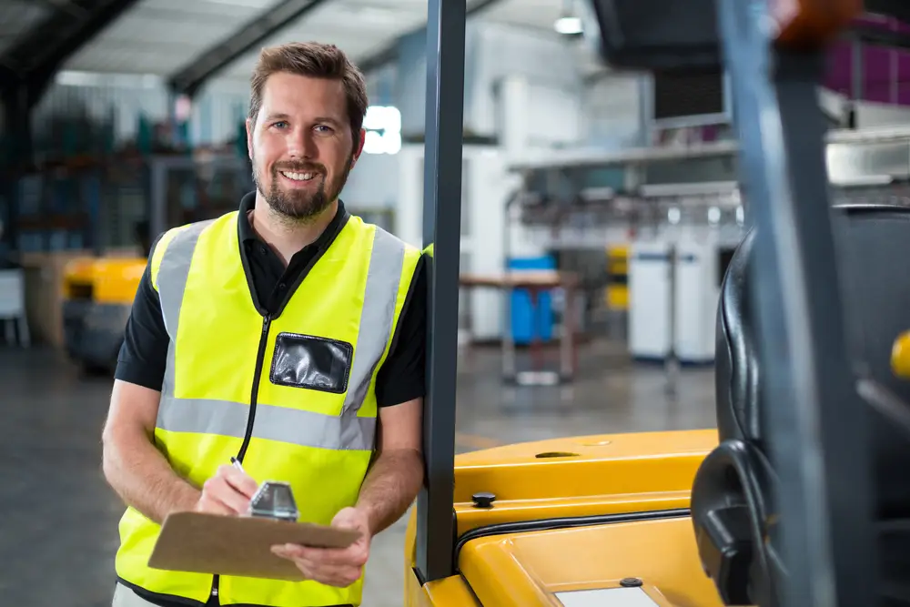 smiling distribution company worker servicing forklift