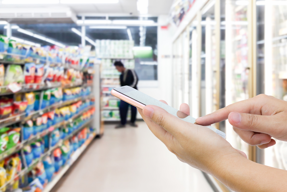 convenience store retailer holding mobile device