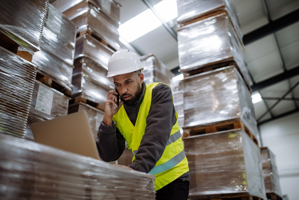 male warehouse manager using distribution software in warehouse