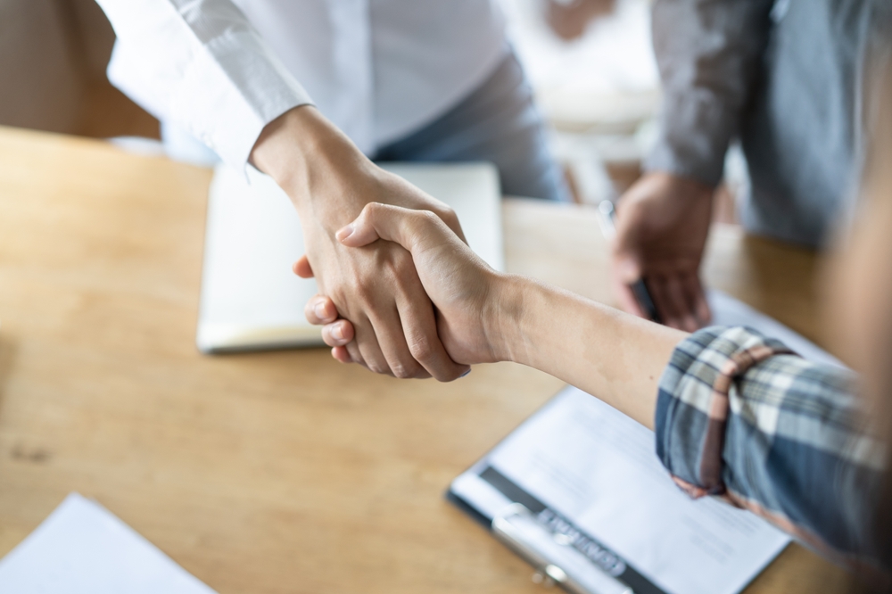 business professionals shaking hands over documents on table