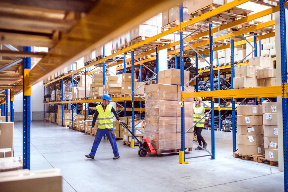 male and female warehouse workers moving pallet of goods