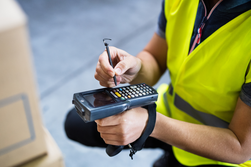 male warehouse worker using mobile rf scanning computer in warehouse