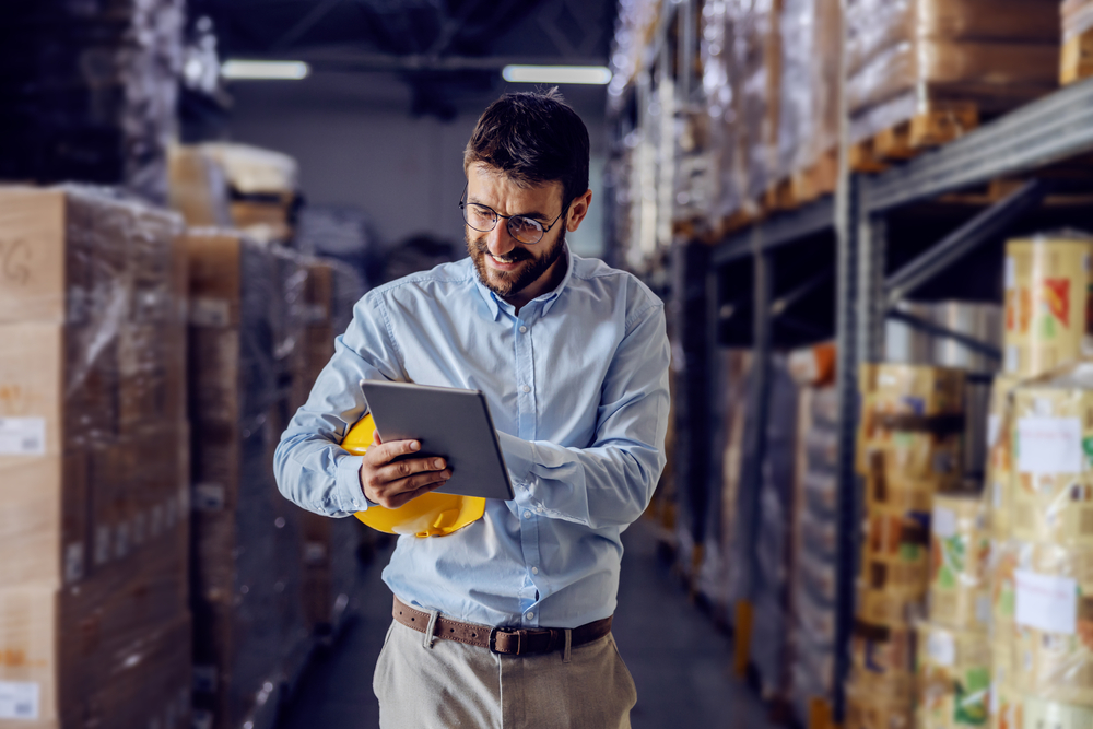 distribution professional smiling at erp tablet computer in warehouse