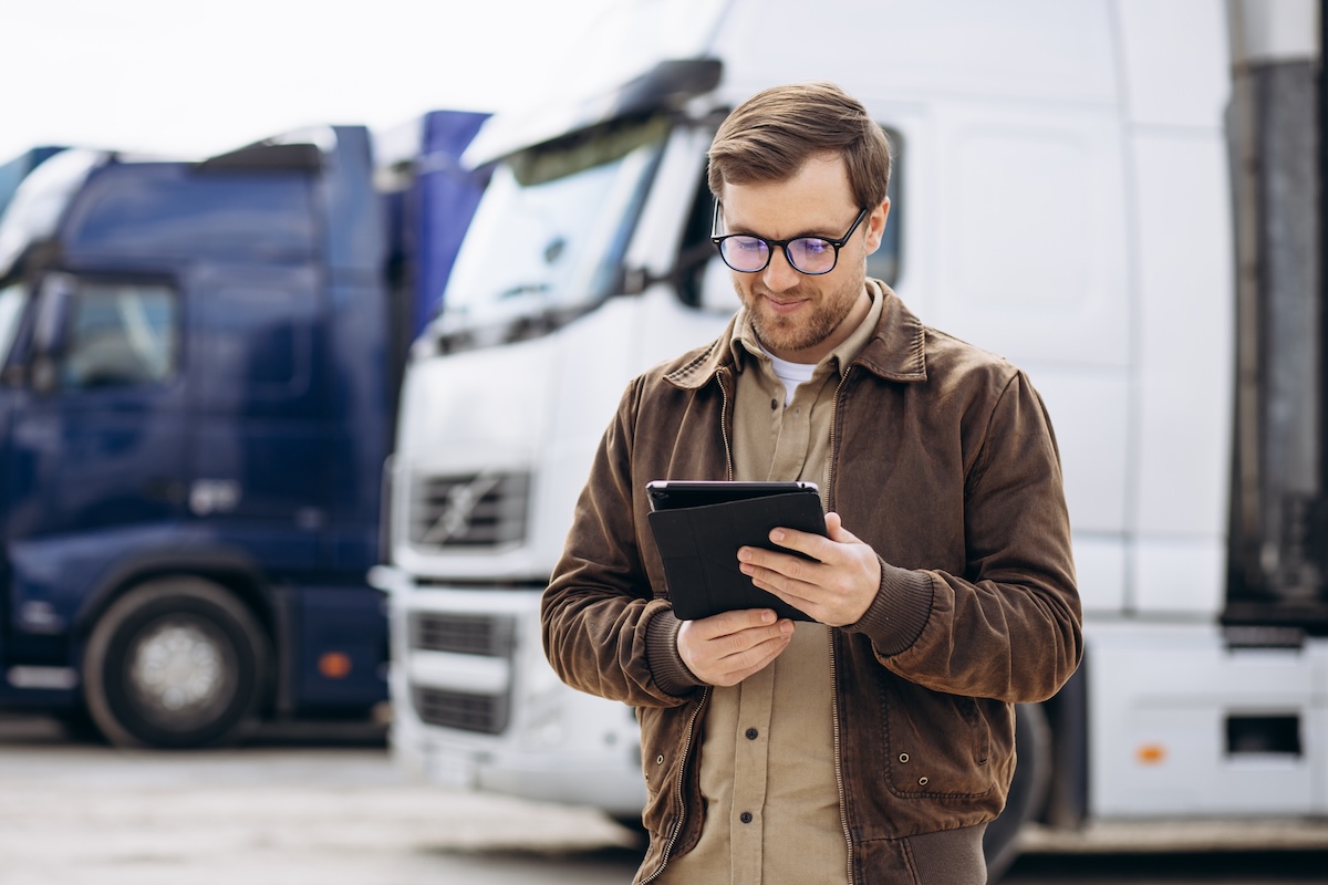 distribution manager using logistics erp software tablet in front of semi trucks