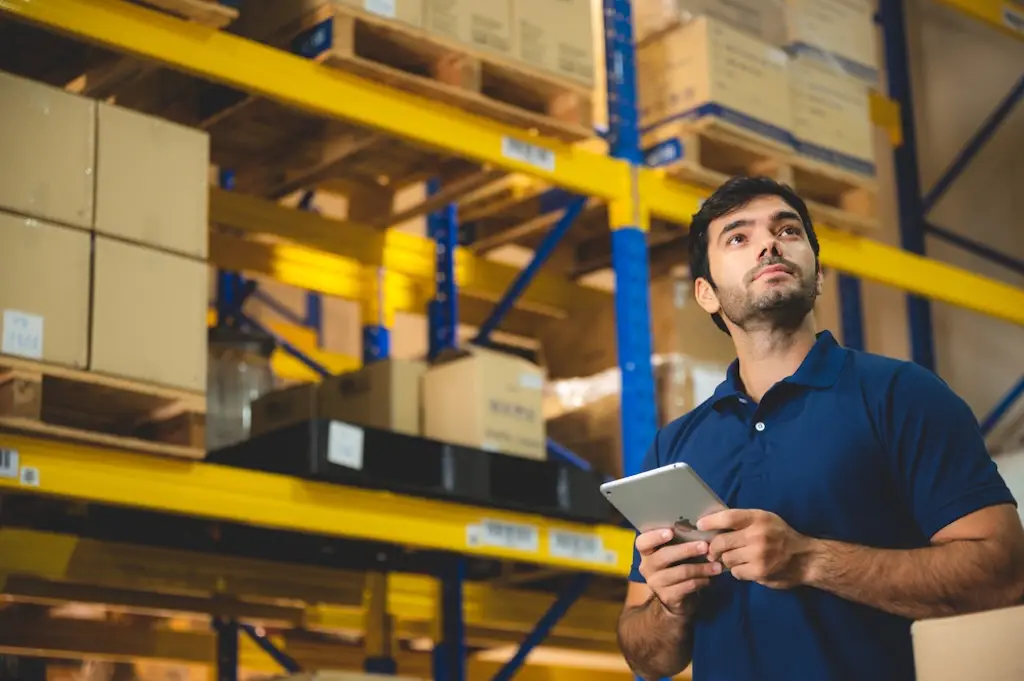 warehouse worker holding inventory management tablet