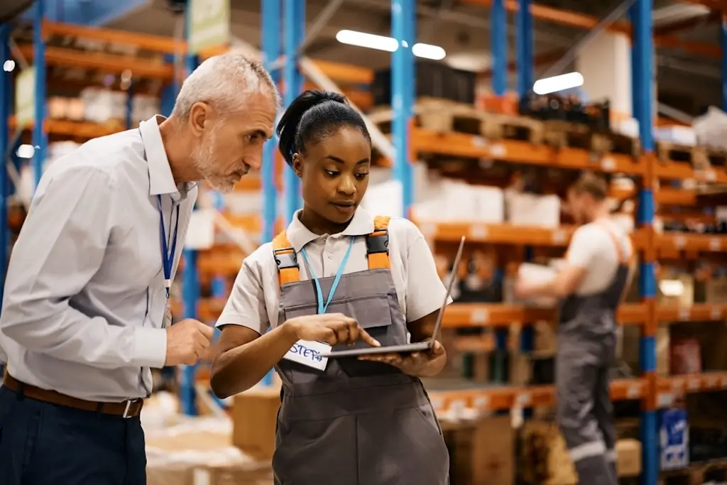 manager and employee looking at warehouse inventory management computer