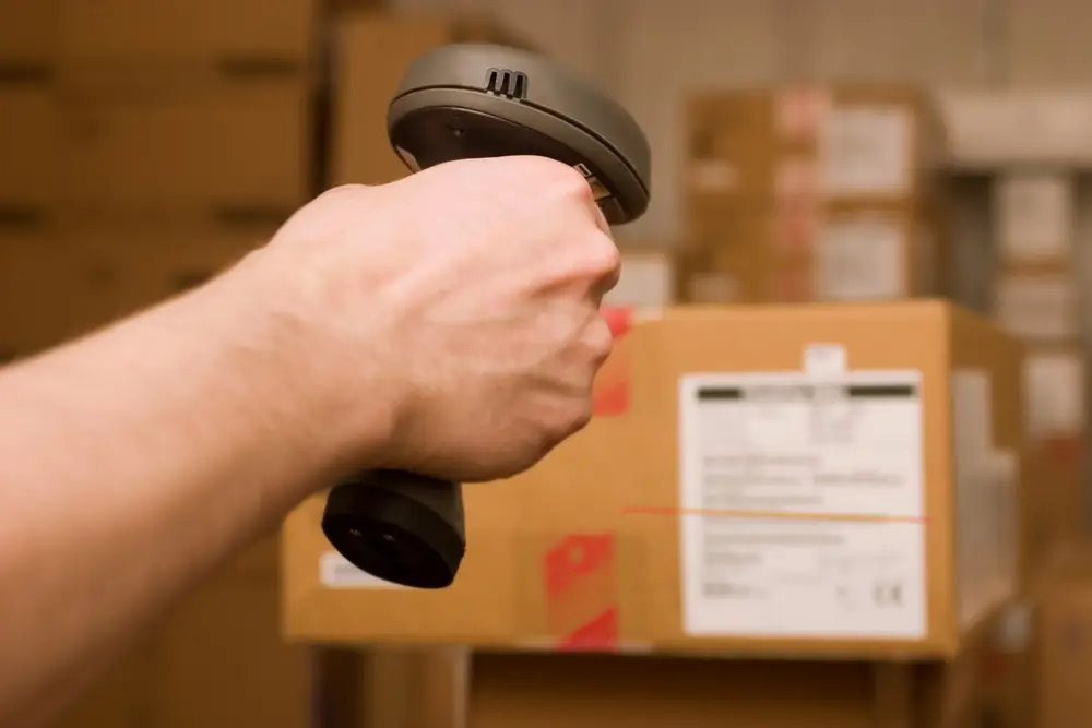 a man's hand using a barcode scanner on a box