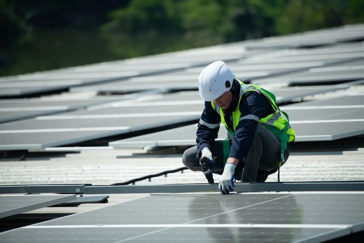 worker installing solar panels on warehouse roof